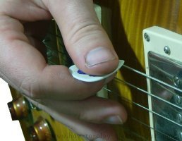 A guitar pick held perpendicular to the guitar body